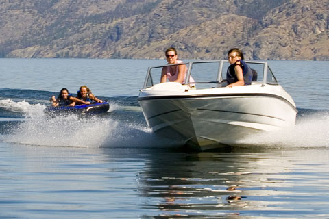 Motor boat towing a tube with two girls on it at a lake
